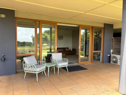 a patio with two chairs and a table and windows at 13th Beach 2-Bedroom Golf Apartment in Connewarre
