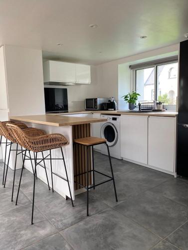 une cuisine avec un comptoir avec des tabourets et une table dans l'établissement Charmante maison proche de la mer et des commerces, à Trégunc