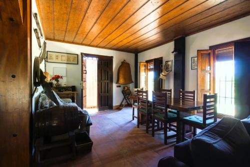 ein Wohnzimmer mit Holzdecke und einem Tisch und Stühlen in der Unterkunft Casa rural con barbacoa y piscina in Ríogordo