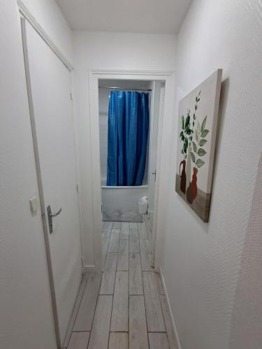 un couloir avec un rideau de douche bleu et du carrelage dans l'établissement Centre, à Dreux