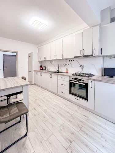 a large kitchen with white cabinets and a table at Nordic Residence NH 42 in Suceava