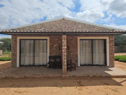 a small brick house with a large window at Kaoko Bush Lodge in Kamanjab