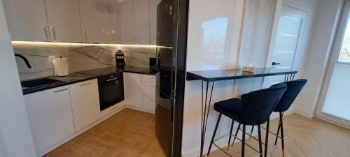 a kitchen with a black refrigerator and two bar stools at Wschód Słońca in Ełk