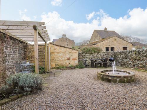 a garden with a fountain and a stone wall at The Old Cobblers in Skipton