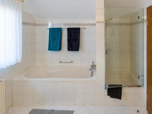 a bathroom with a tub and a shower with blue towels at Ferienwohnung am Hochblauen in Badenweiler
