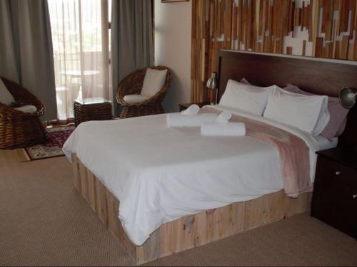 a bedroom with a large bed with white sheets and pillows at Diplomat Boutique Self-Catering in Klein Windhoek