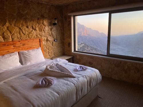 a bedroom with a bed and a large window at Dana Trail Hotel in Dana