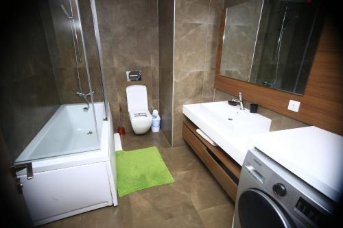 a bathroom with a toilet and a sink and a washing machine at PLS Apartments Pearl-Cantonment One Bedroom in Nima