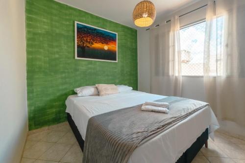 a green bedroom with a bed with two towels on it at Amplo Aptº em Maringá - Excelente Localização! in Maringá
