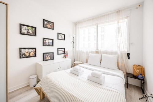 une chambre blanche avec un grand lit et une fenêtre dans l'établissement Amelot Mobilite, à Paris