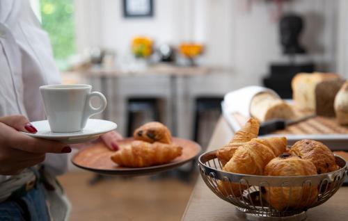 a person holding a cup of coffee and a bowl of pastries at Maison D'Anthouard in Écully