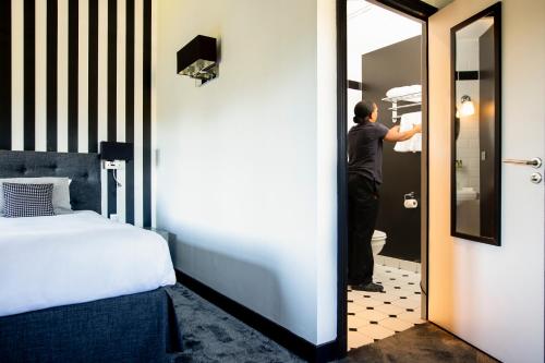 a man standing in a hotel room looking in the mirror at Maison D'Anthouard in Écully
