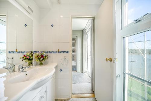 a white bathroom with a sink and a window at No 26 The Salcombe in Salcombe