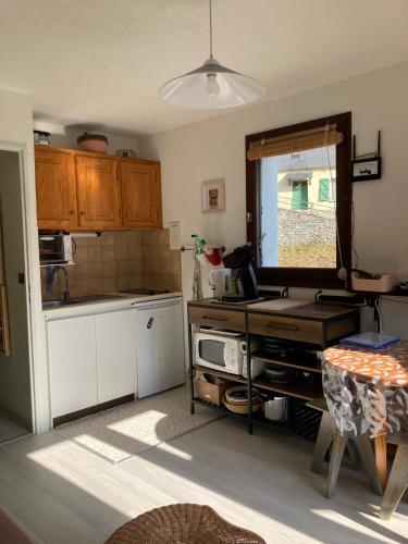 une cuisine avec des armoires en bois, une table et une fenêtre dans l'établissement L'Adret, à Barèges