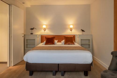 a bedroom with a large bed with two pillows at Hotel Ter Duinen in Bruges