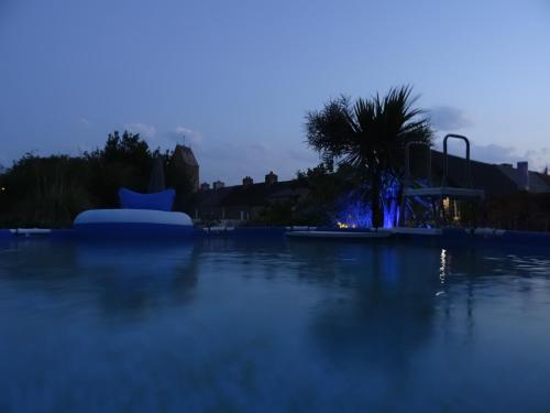 a swimming pool at night with a playground at Gîte "ROSE des SABLES" - PISCINE jusqu'au 15 SEPTEMBRE, JARDIN BOTANIQUE, COMMERCES &MER in Surtainville