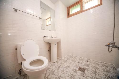 a white bathroom with a toilet and a sink at Pohang Rainbow Pension in Pohang