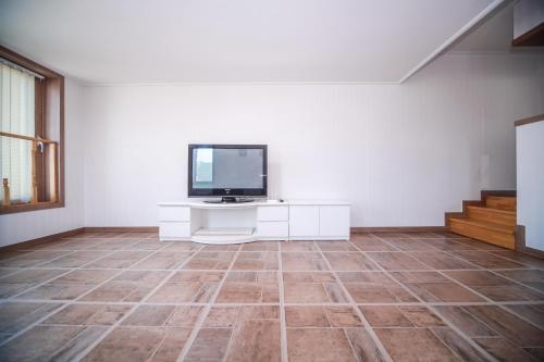 a living room with a tv on a white wall at Pohang Rainbow Pension in Pohang