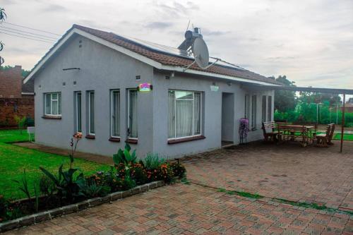 a small white house with a patio and a table at 2Bed-4Guests-Garden-NearCentre&Attractions in Harare