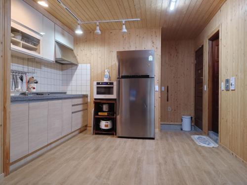 a large kitchen with a stainless steel refrigerator at Danyang mulgoeul pension in Danyang