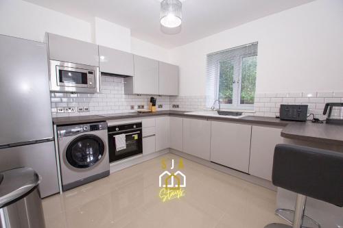 a kitchen with white cabinets and a washer and dryer at Affleck Retreat 4 - SJA Stays - Modern 1 Bed Apartment in Aberdeen