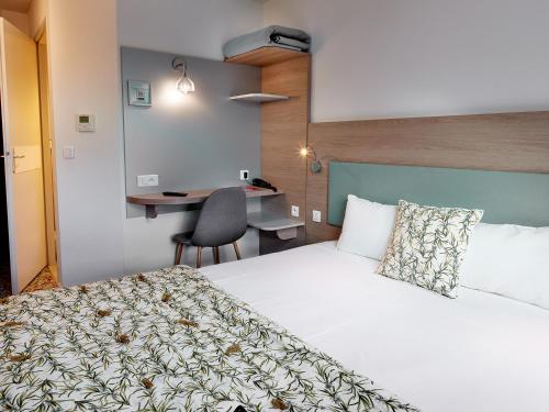 a hotel room with a bed and a desk at Hôtel REVOTEL Nancy Centre Gare et Congrès in Nancy