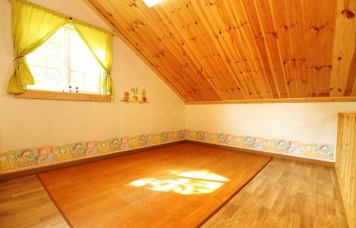 an attic room with a wooden floor and a window at Cheongju Okhwadaestory Pension in Cheongju