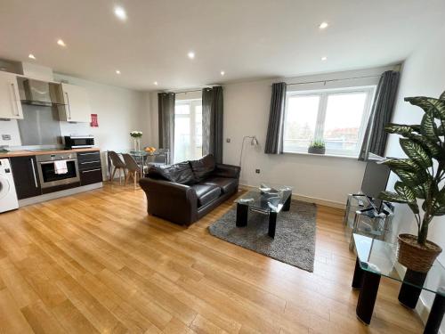 a living room with a black leather couch and a kitchen at Blue Sky Apartments@ Abbots Yard, Guildford in Guildford
