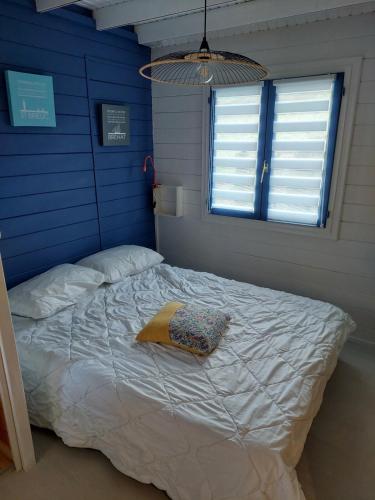 un lit dans une chambre avec un mur bleu dans l'établissement Le petit Bachelet - Chalet tout confort à la mer, à Plérin