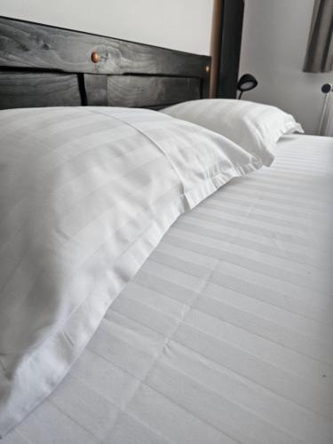 a close up of a bed with white sheets and pillows at Pensiunea Miruna in Moieciu de Jos