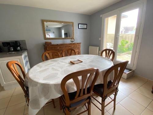 une salle à manger avec une table et des chaises blanches dans l'établissement Appartement 3 pièces cœur Riva Bella, à Ouistreham