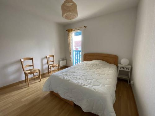 une chambre avec un lit et deux chaises et une fenêtre dans l'établissement Appartement T2 avec piscine, proche thermes, terrasse, parking, petit animal OK, Cambo-les-Bains - FR-1-495-142, à Cambo-les-Bains