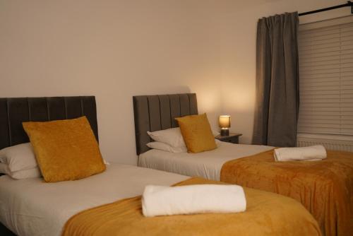 a room with two beds with orange and white pillows at Harborne Park House in Birmingham