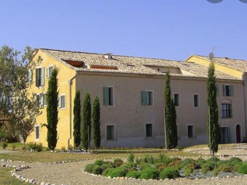 un grand bâtiment jaune avec des arbres devant lui dans l'établissement Appartement confortable avec piscine au cœur du plateau de Valensole - FR-1-822-6, à Brunet