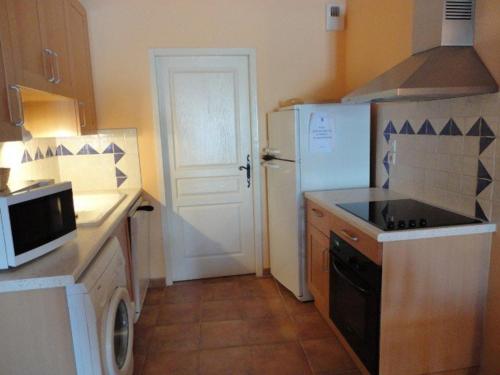 Il comprend une cuisine équipée d'un réfrigérateur blanc et d'une cuisinière. dans l'établissement Studio cosy avec piscine au cœur du plateau de Valensole - FR-1-822-13, à Brunet