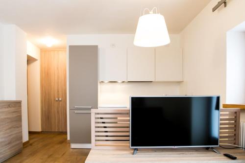a flat screen tv in a kitchen with white cabinets at Mirtillo Blu Family Apartment in Alagna Valsesia