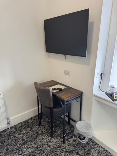a desk with a chair and a television on a wall at The Royal Hotel Elgin in Elgin