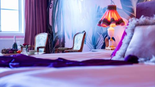 a bedroom with a bed with a lamp and chairs at Slottsgården Hotell & Restaurang in Vadstena