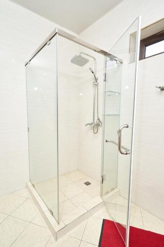 a glass shower in a bathroom with a red rug at Rakat Plaza in Tashkent