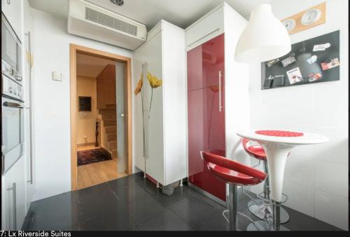 a small kitchen with a red stool and a table at LxRiverside Suite Apartment in Lisbon
