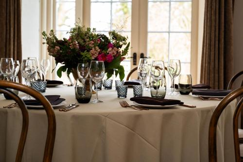 a table with wine glasses and a vase of flowers at Tottington Manor Hotel in Henfield