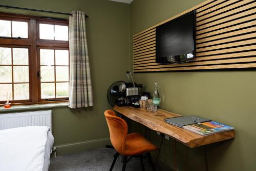 a room with a desk with a television on a wall at Tottington Manor Hotel in Henfield