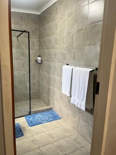 a bathroom with a shower with white towels at African Kingdom Guest House in Boksburg