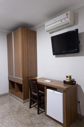 a room with a desk and a tv on the wall at BOMBONATO HOTEL - Fácil Acesso ao Aeroporto e parque de Exposições ABCZ in Uberaba