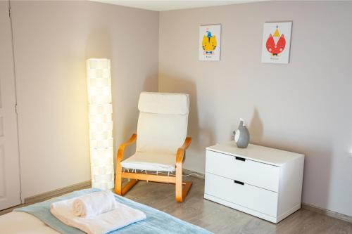 a bedroom with a chair and a bed and a dresser at À La Motte Cinema, Park BY PRIMO C0NCIERGERIE in Cuisery