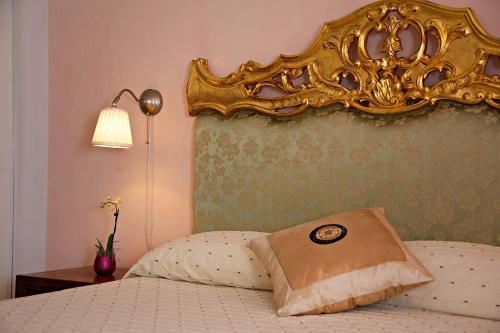 a bed with a gold headboard with a pillow on it at Villa Lieta in Ischia