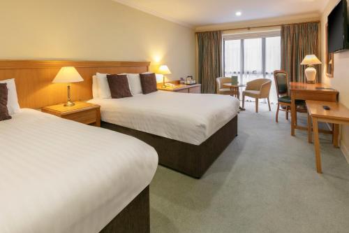 a hotel room with two beds and a desk at Knights Hill Hotel & Spa in Kings Lynn