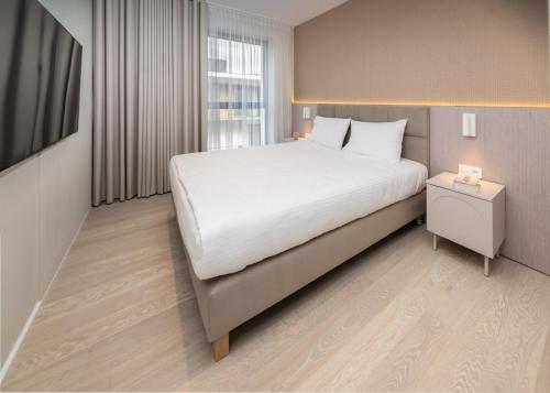 a bedroom with a large white bed and a window at Apartamenty na Półwyspie Wydma&Las in Jastarnia