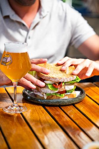 a sandwich on a plate with a glass of beer at Hotel Villa Ruimzicht in Doetinchem