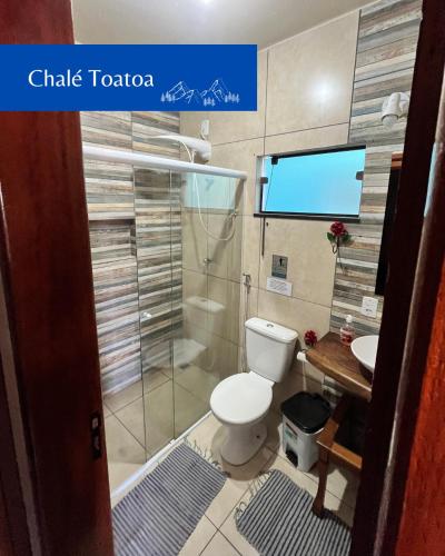 ein Bad mit WC und ein TV an der Wand in der Unterkunft Chalés Toatoa e Tô de Boa - Conceição de Ibitipoca in Lima Duarte